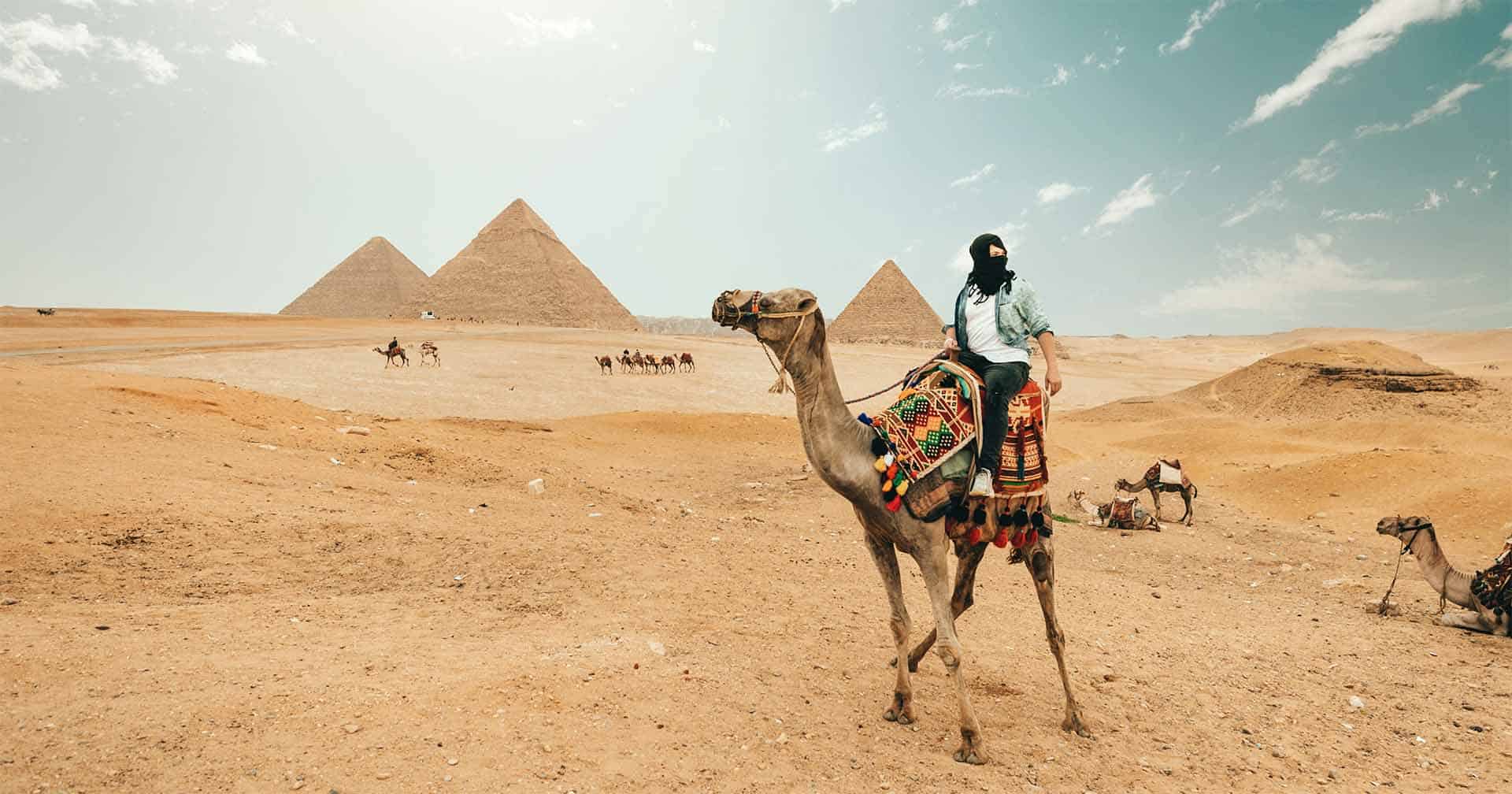 Traveler on a camel in front of the Pyramids of Giza in Egypt during a luxury custom tour by Osiris Tours